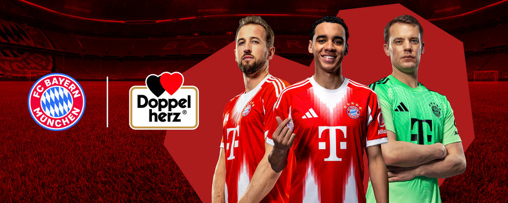 Three football players model the new FC Bayern München team kits on a vibrant red background. The left player wears a red and white jersey; the center player sports a similar design; the right player, a goalkeeper, wears a green jersey. The FC Bayern logo and "Doppel herz" branding are displayed.
